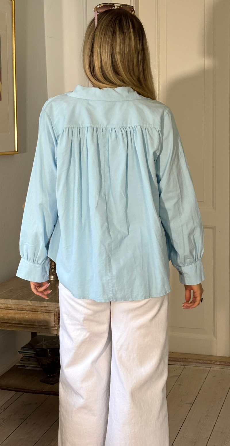 Otella fløjlsbluse med v-hals og flæsekant lysblå LikeLondon