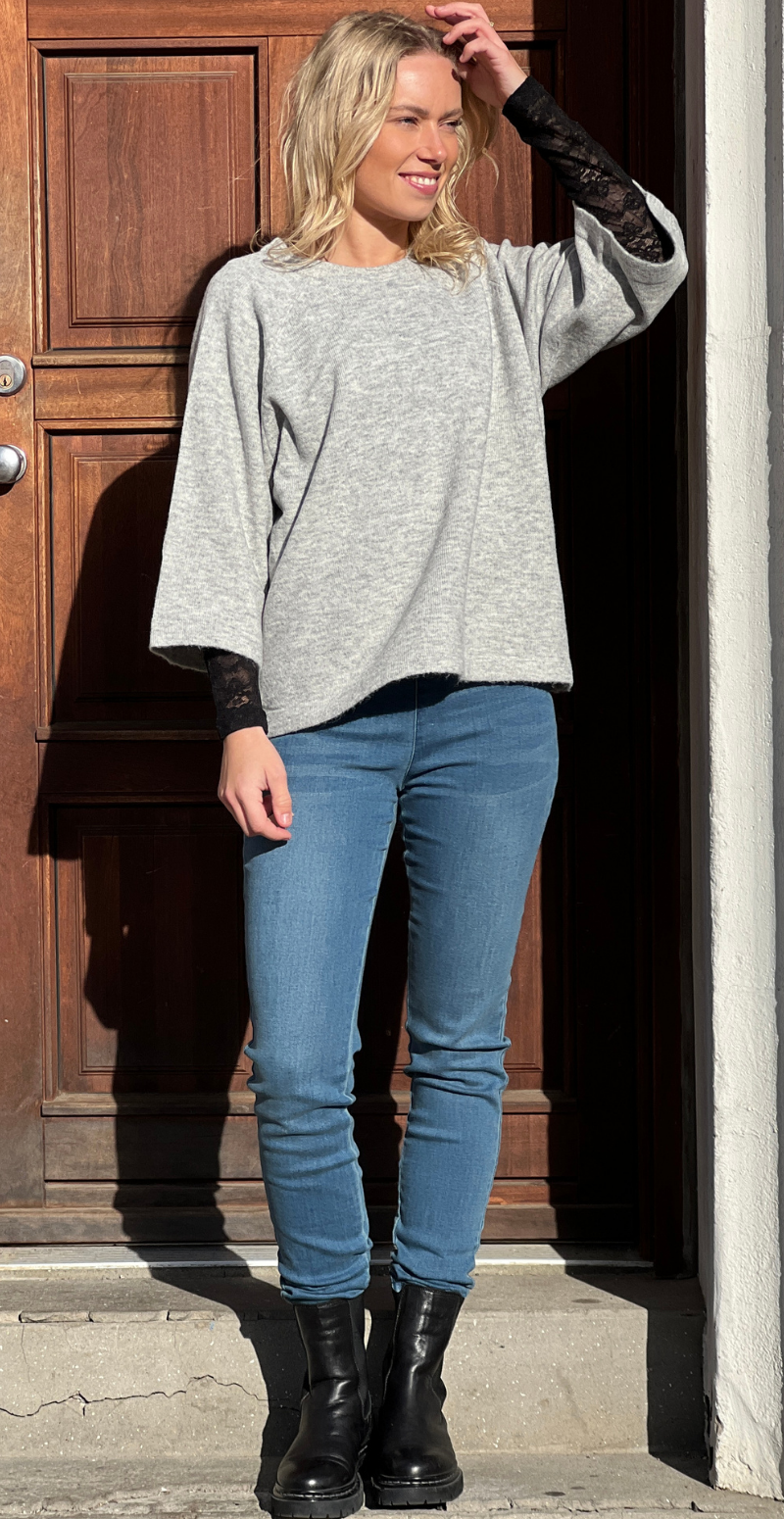 Kvinde i grå Orlean strik med 3/4 ærmer og blå jeans forfra.