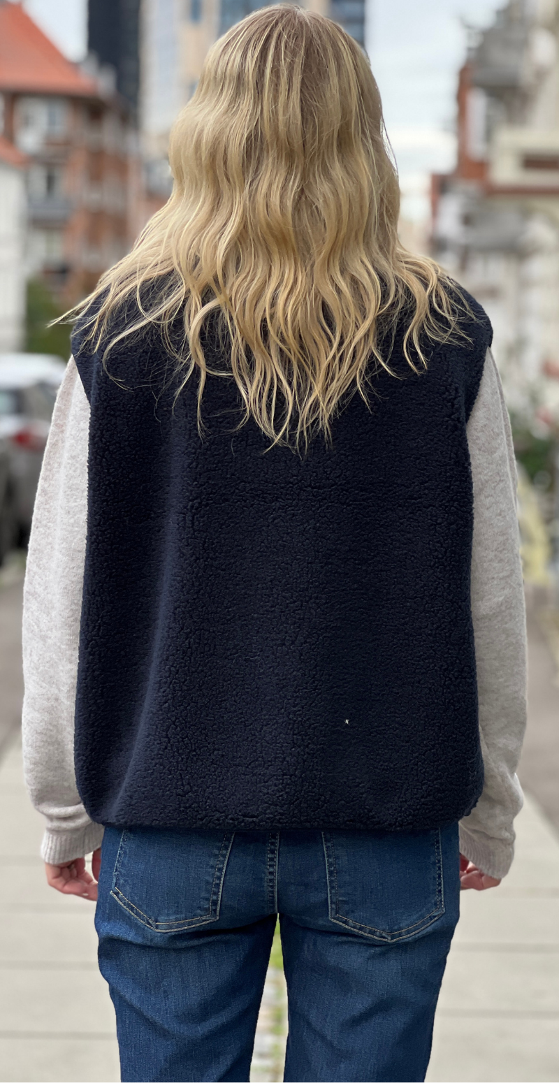 Bagfra: Onyx vest i navy teddy fra LikeLondon.com med lange beige ærmer og blå jeans.