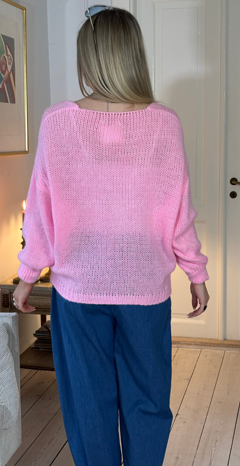 Zinka strik med lange ærmer og knude foran pink LikeLondon