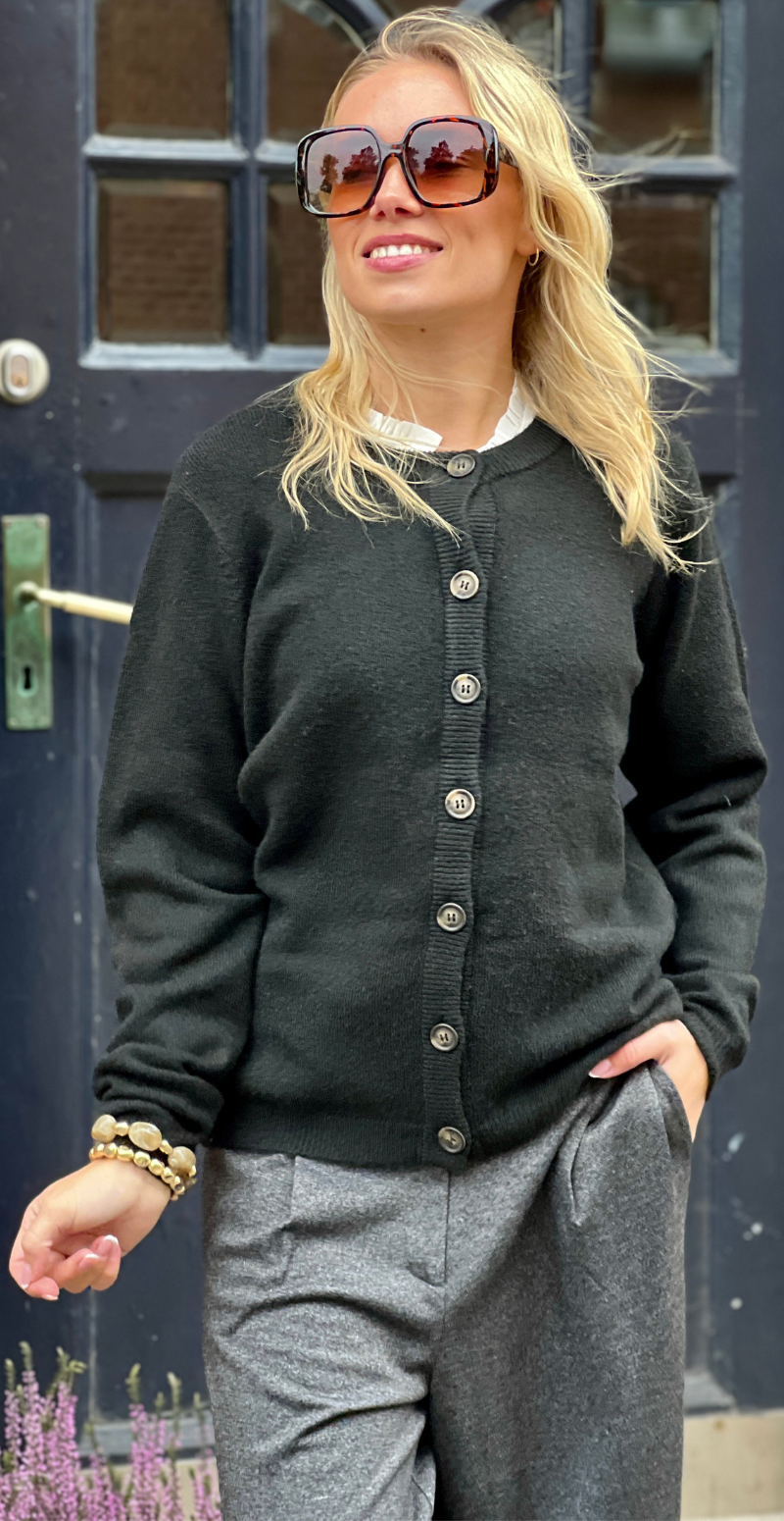 Kvinde i sort Orlean strik cardigan fra LikeLondon.com med knapper forfra.