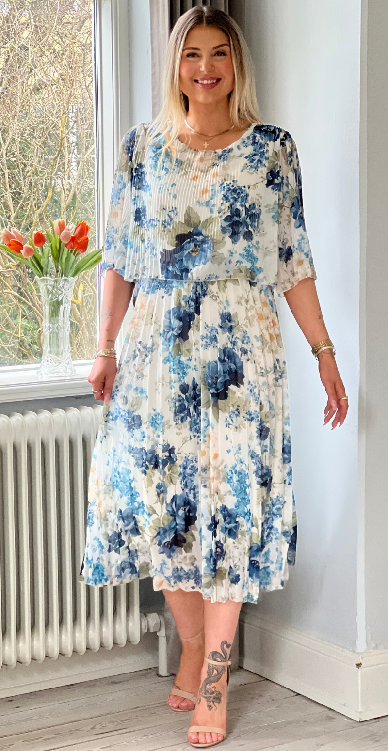Blomstret maxikjole i let, strækbar stof med blå, grønne og beige nuancer – elegant og komfortabel til forårets og sommerens anledninger, forhandles hos LikeLondon.