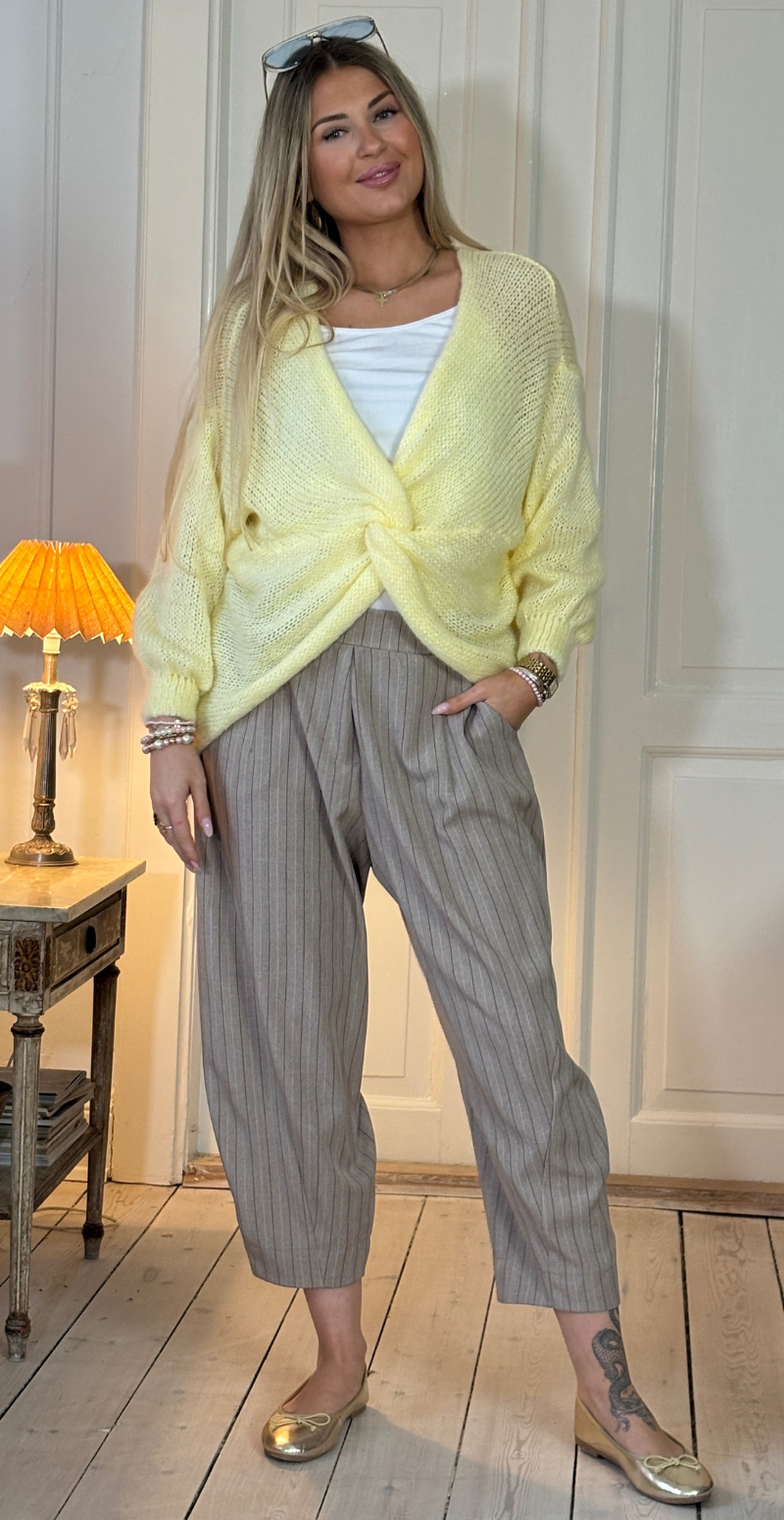 Zinka strik med lange ærmer og knude foran gul LikeLondon