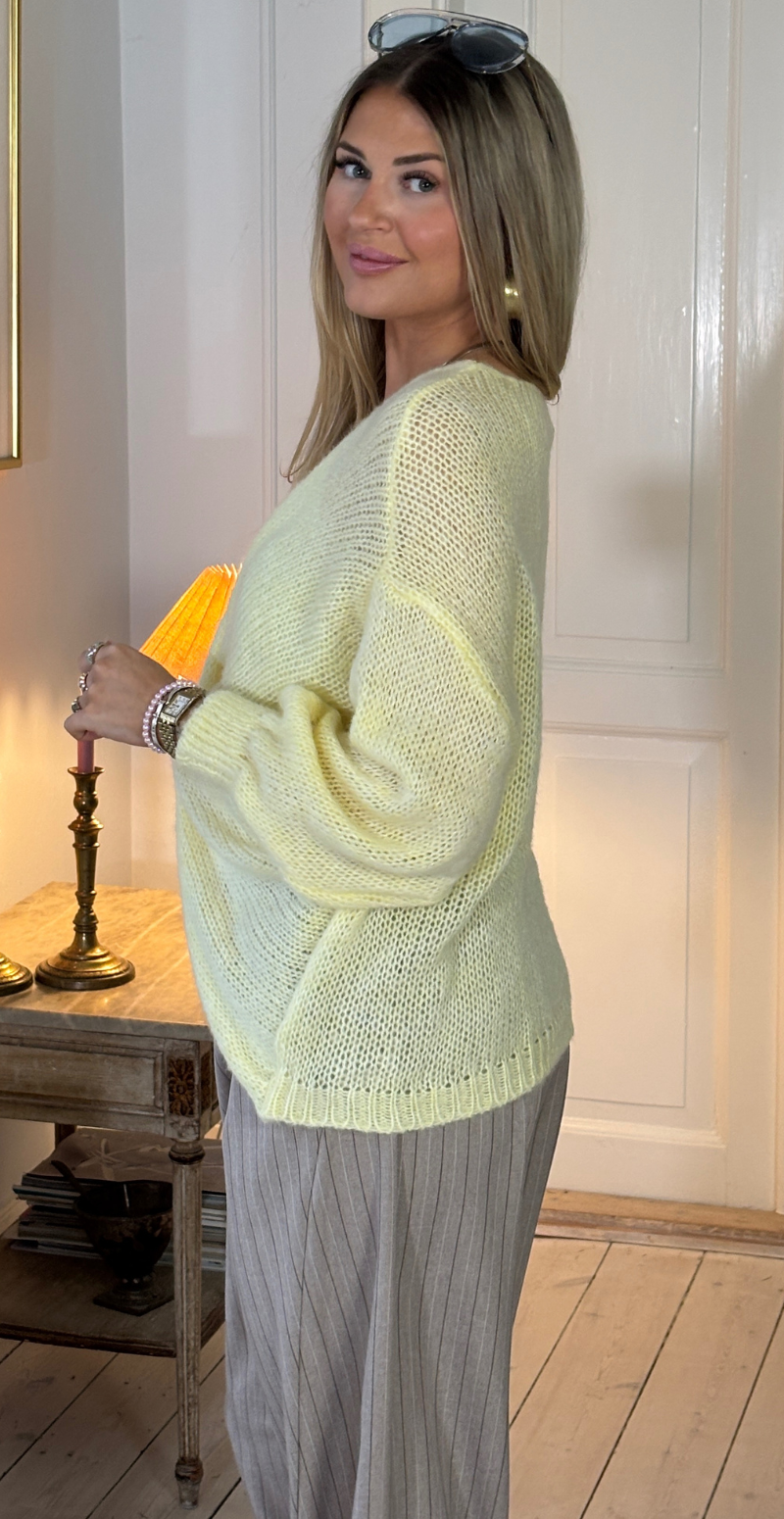 Zinka strik med lange ærmer og knude foran gul LikeLondon