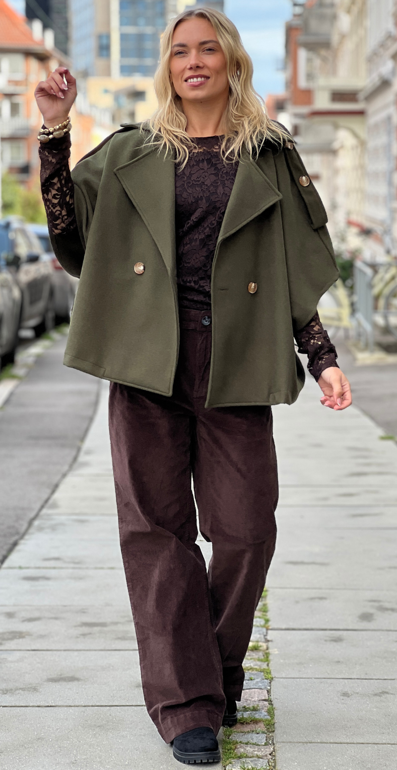 Kvinde i Cleo kort poncho jakke i military grøn med knapper forfra fra LikeLondon.com