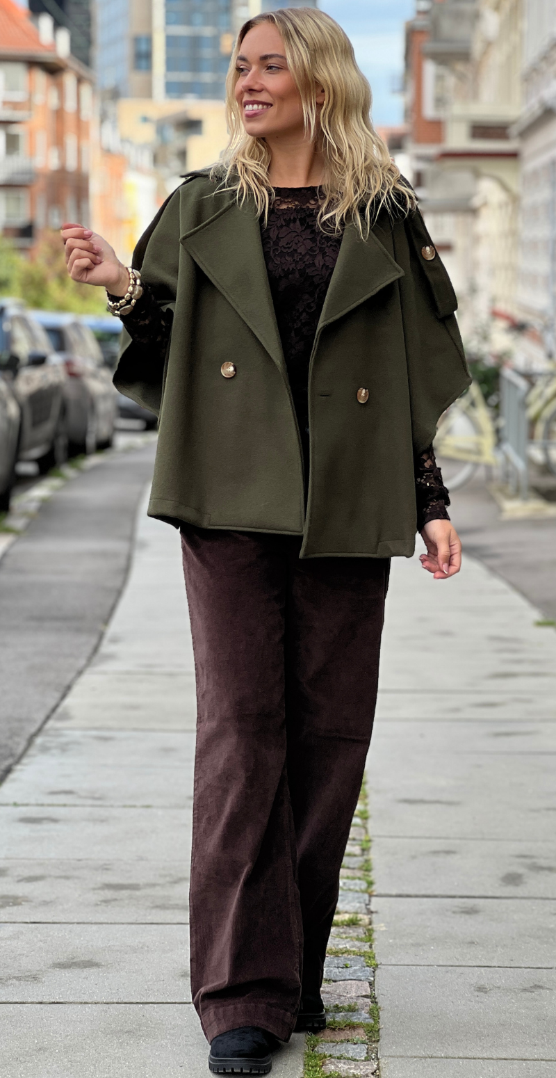 Kvinde i olivengrøn Cleo kort poncho jakke fra LikeLondon.com med knapper fortil, set forfra.