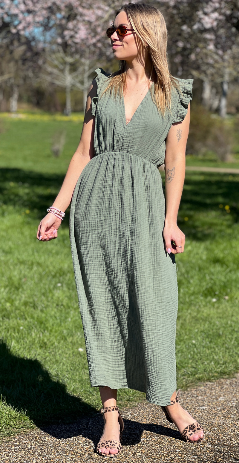 Elegant, lang salviegrøn maxikjole med V-udskæring, rynket tekstur og flæseærmer - stylet med leopard-print stroppesandaler og solbriller, forhandles hos LikeLondon.