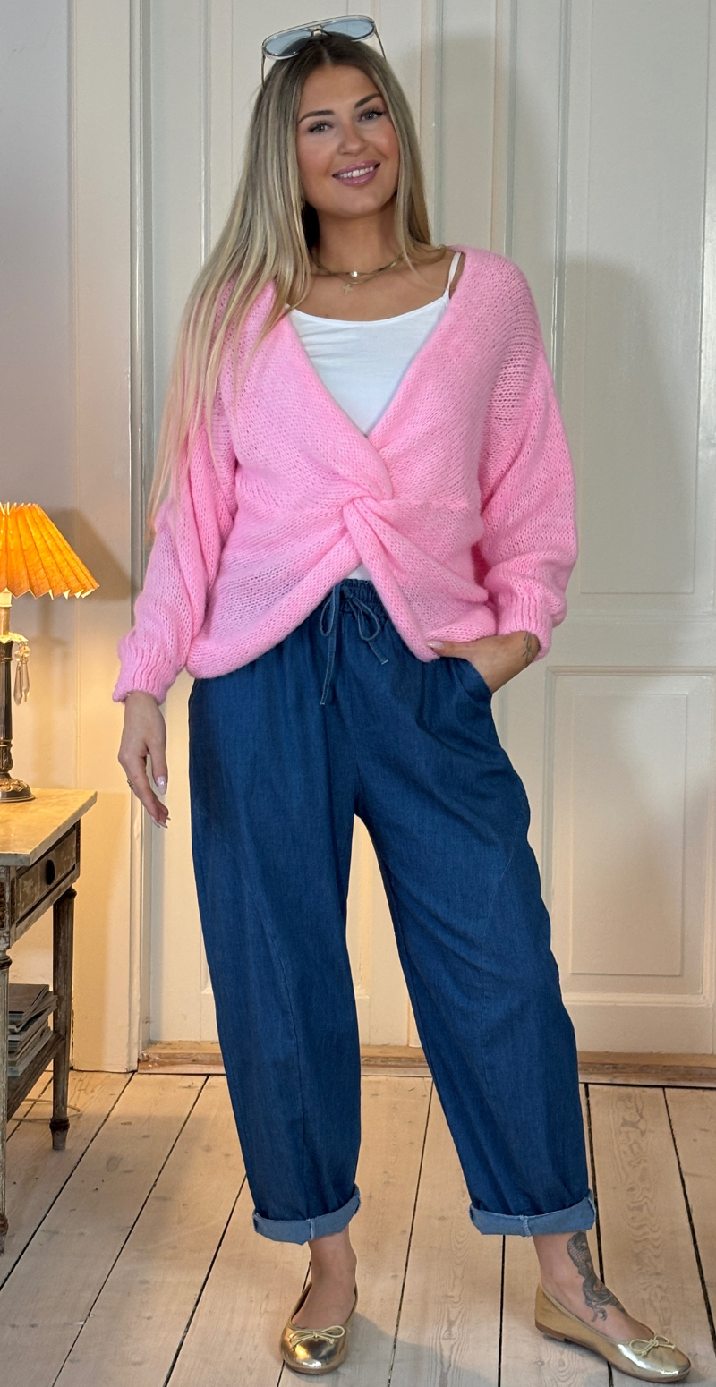 Zinka strik med lange ærmer og knude foran pink LikeLondon