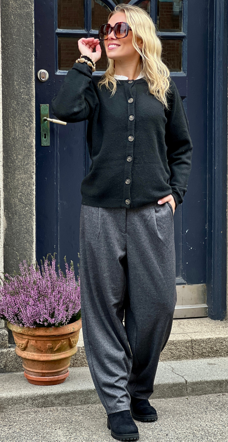 Kvinde i sort Orlean strik cardigan forfra med grå bukser og solbriller.