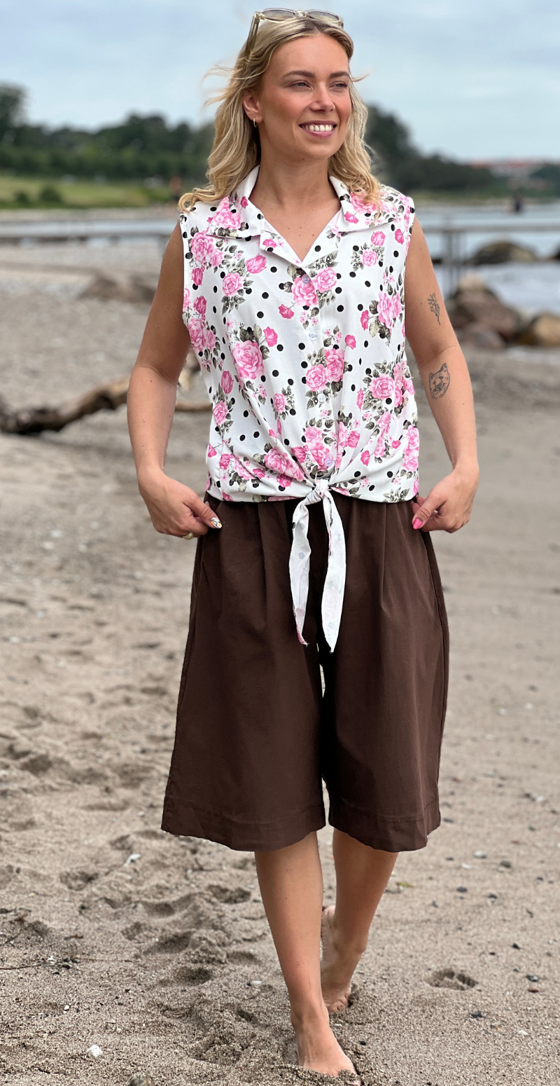 Ulla blomstret top med knapper og bindedetalje foran pink LikeLondon