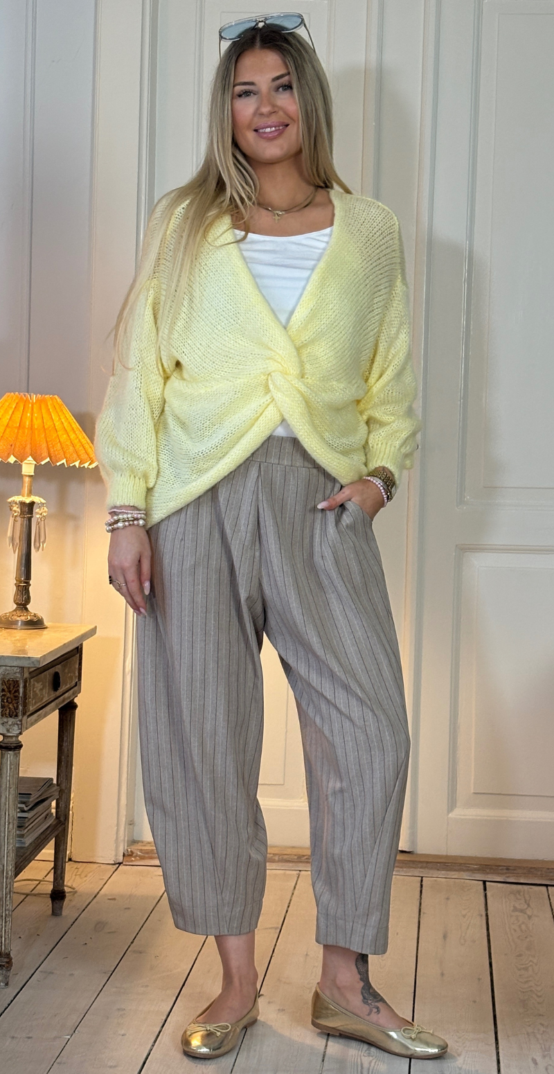 Zinka strik med lange ærmer og knude foran gul LikeLondon