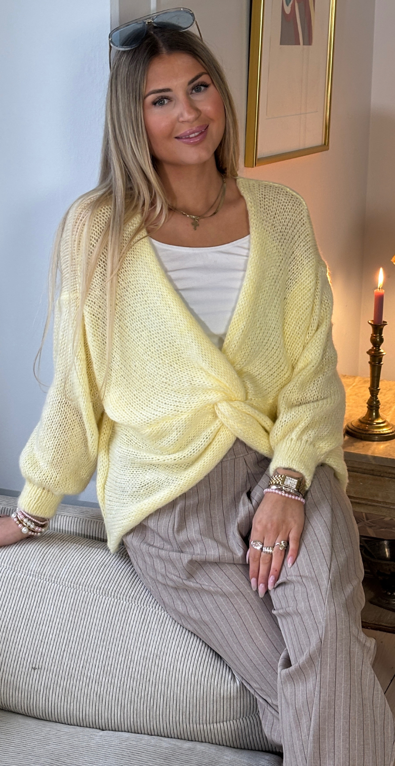 Zinka strik med lange ærmer og knude foran gul LikeLondon