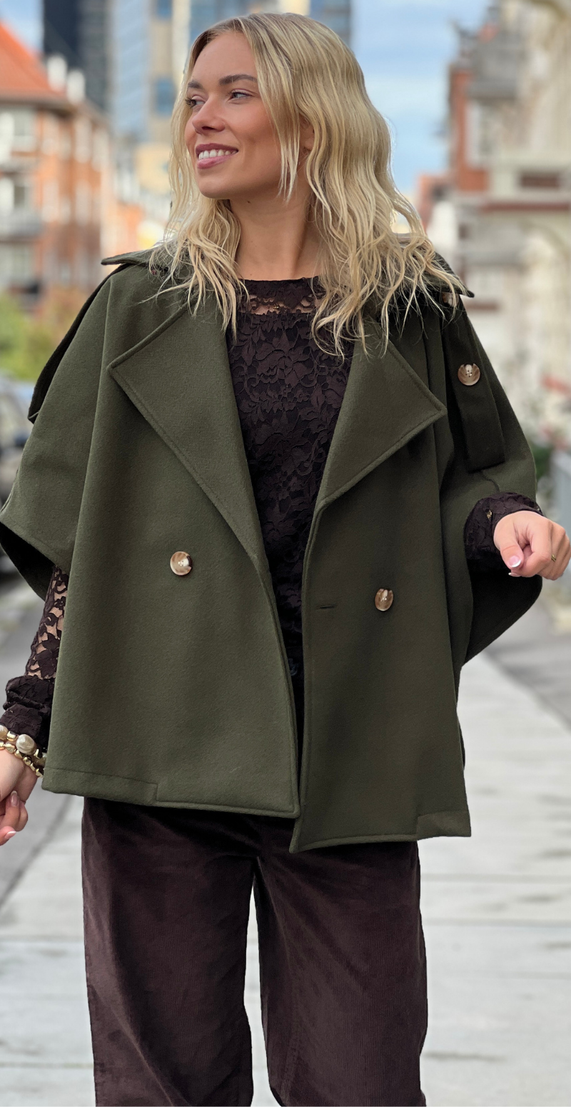 Kvinde i military grøn Cleo kort poncho jakke fra LikeLondon.com med knapper forfra.