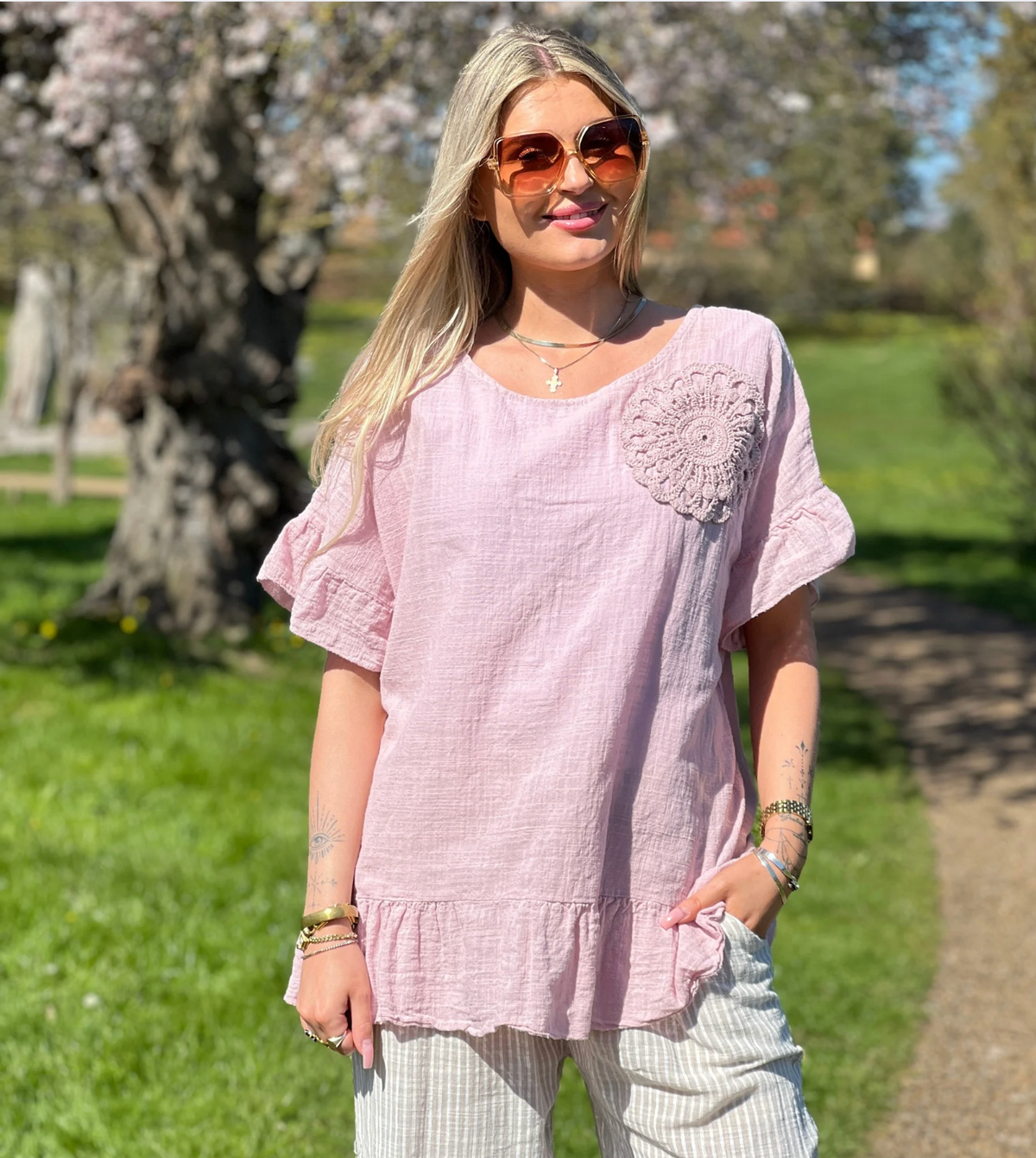 Kvinde i rosa Carolina kortærmet bluse med peplum og hæklet blomst set forfra.